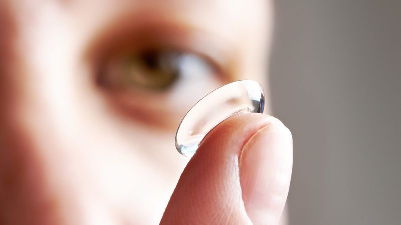 A soft contact lens balanced on a fingertip